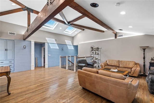 living room with visible vents, a skylight, high vaulted ceiling, beamed ceiling, and light wood-style flooring
