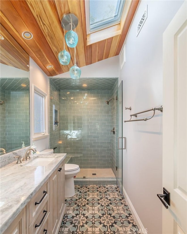 bathroom featuring vanity, toilet, tile patterned floors, a stall shower, and a skylight