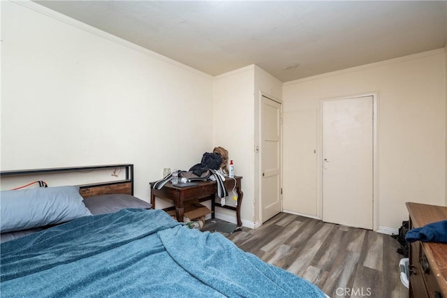 bedroom featuring baseboards, ornamental molding, and wood finished floors