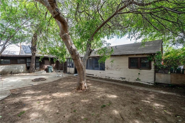 back of property with a fire pit and a patio