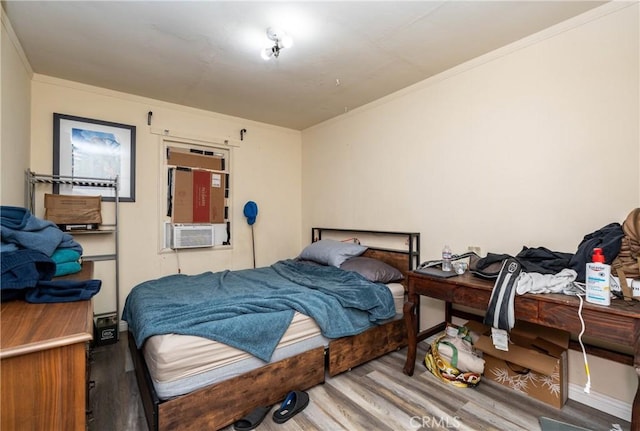 bedroom featuring cooling unit, wood finished floors, and ornamental molding
