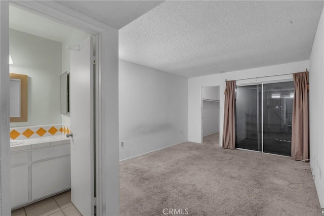 unfurnished bedroom with a spacious closet, light carpet, and a textured ceiling