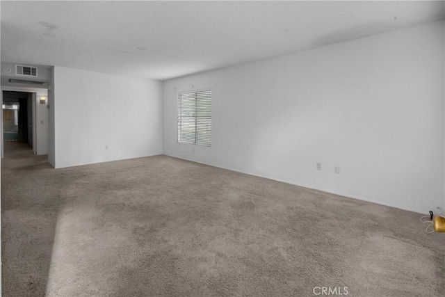 empty room featuring a textured ceiling, visible vents, and carpet
