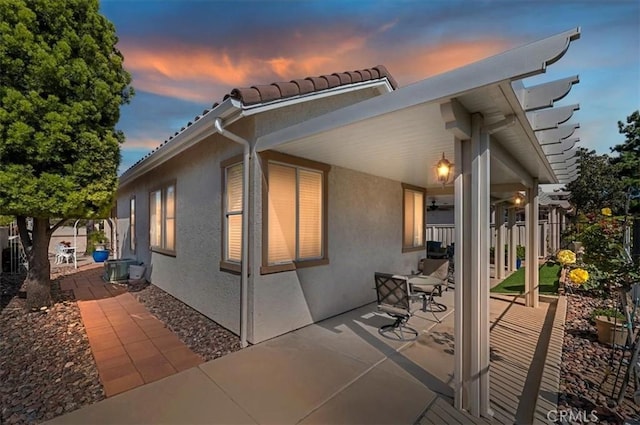 40636 Via Jalapa, Murrieta, CA 92562 - back of house at dusk with fence, a patio, stucco siding, and a tiled roof