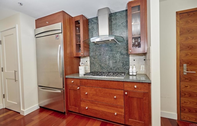 700 W E St Unit 2802, San Diego, CA 92101 - kitchen featuring appliances with stainless steel finishes, wall chimney exhaust hood, dark wood finished floors, decorative backsplash, and brown cabinetry