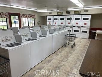 community laundry room featuring washer and clothes dryer and light tile patterned flooring