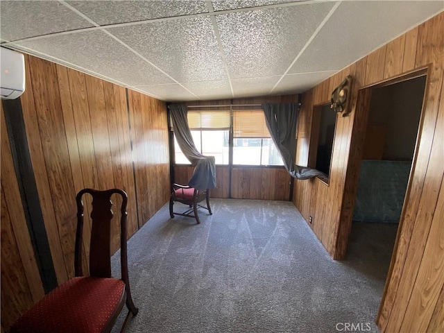 sitting room with a wall mounted AC, wooden walls, and carpet floors