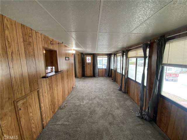 hall with wood walls and light carpet