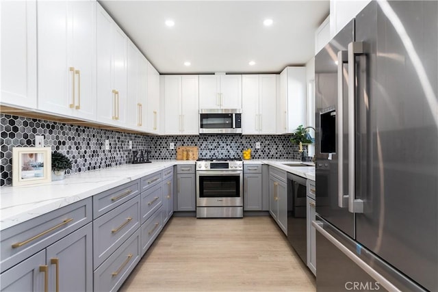 9038 Whitaker Ave, Northridge, CA 91343 - kitchen featuring appliances with stainless steel finishes, gray cabinetry, light wood-style floors, decorative backsplash, and light stone countertops