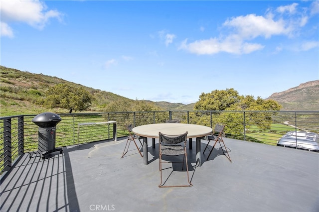 view of patio featuring outdoor dining area, a mountain view, and a grill