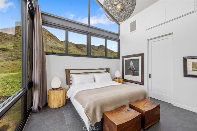 bedroom featuring a towering ceiling, dark tile patterned flooring, and visible vents