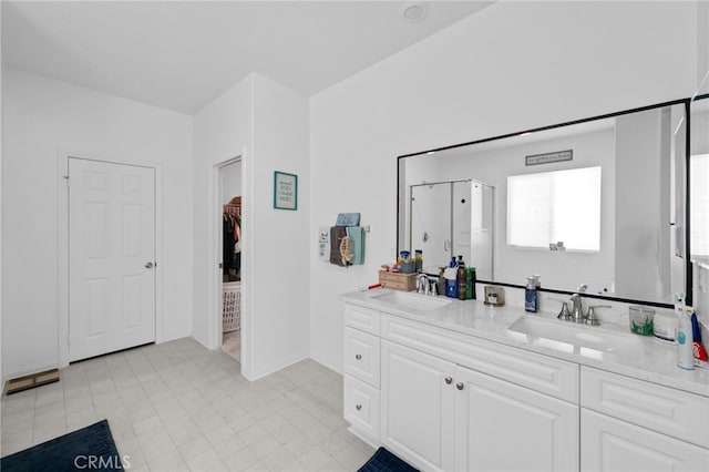 bathroom featuring baseboards, double vanity, a sink, and a stall shower