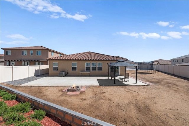 rear view of property featuring an outdoor fire pit, a gazebo, a tile roof, and a patio