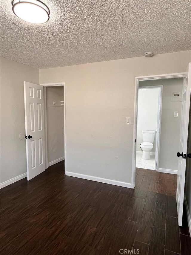 unfurnished room with dark wood-type flooring, baseboards, and a textured ceiling