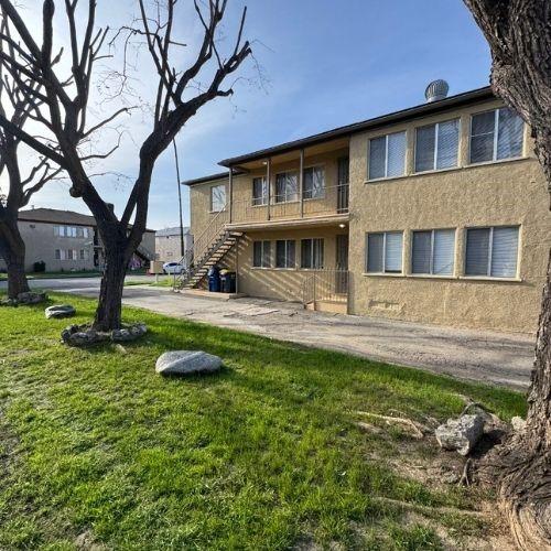 exterior space featuring stairway, stucco siding, and a yard