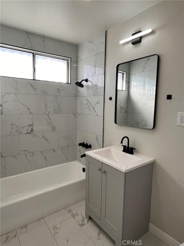 bathroom with marble finish floor, vanity,  shower combination, and baseboards