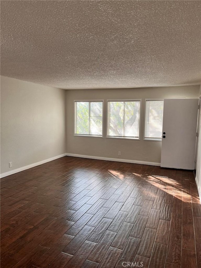 unfurnished room with dark wood-style flooring, baseboards, and a textured ceiling