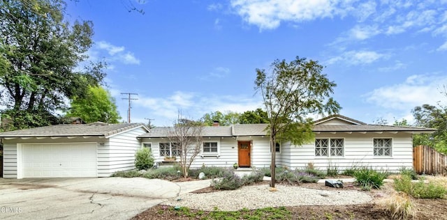 ranch-style home with an attached garage, fence, a chimney, and concrete driveway