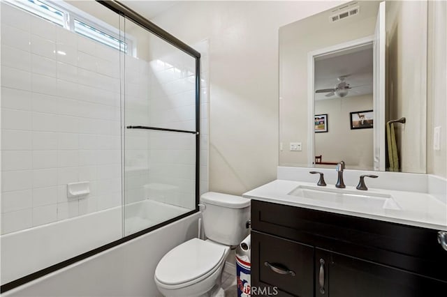 bathroom featuring visible vents, toilet, ceiling fan, enclosed tub / shower combo, and vanity