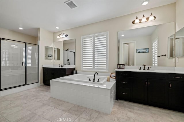 full bathroom featuring two vanities, a stall shower, a garden tub, visible vents, and a sink