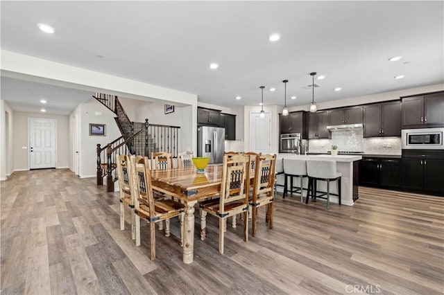 dining room featuring recessed lighting, light wood-style flooring, and stairs