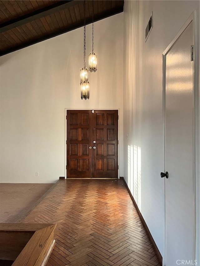 foyer entrance with a chandelier, visible vents, beam ceiling, and a high ceiling