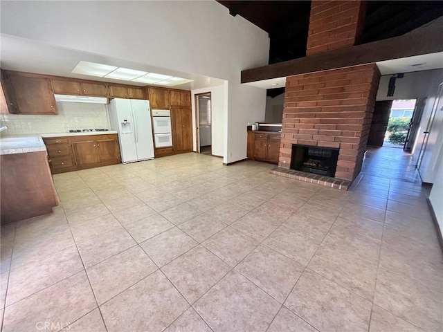kitchen featuring tasteful backsplash, a sink, light countertops, white appliances, and brown cabinets