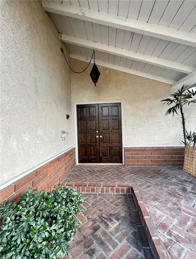 view of exterior entry with stucco siding and brick siding