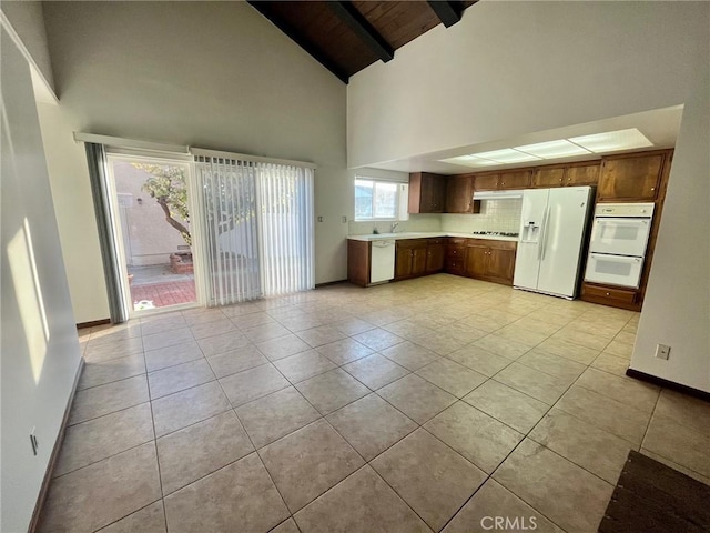 kitchen with baseboards, white appliances, light countertops, beam ceiling, and wooden ceiling