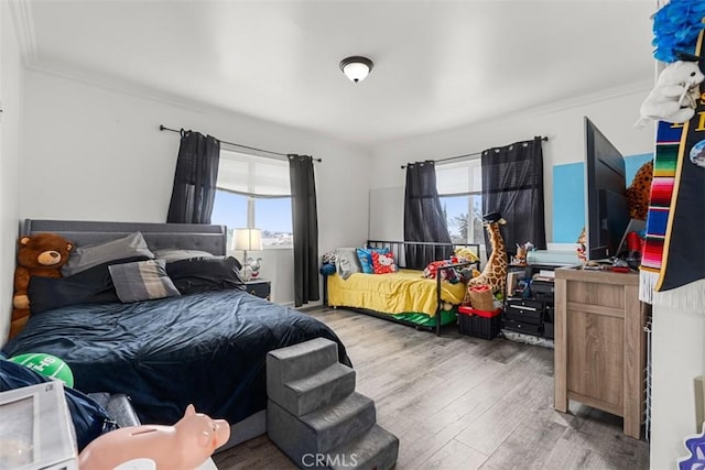bedroom featuring crown molding, multiple windows, and wood finished floors