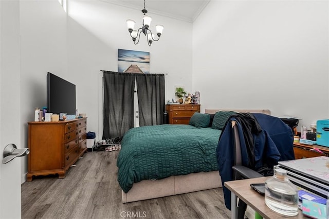 bedroom featuring a chandelier, ornamental molding, and wood finished floors