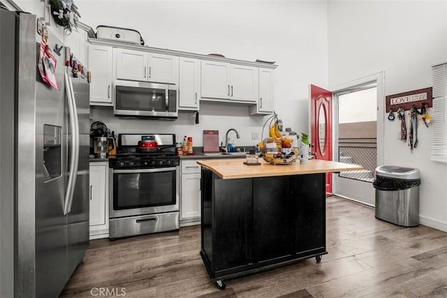 kitchen with stainless steel appliances, butcher block countertops, a sink, and wood finished floors