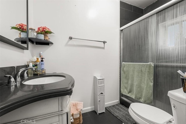 bathroom with a shower with shower door, vanity, baseboards, and toilet