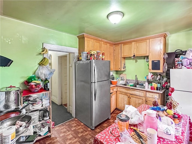kitchen featuring light countertops, a sink, light brown cabinetry, and freestanding refrigerator