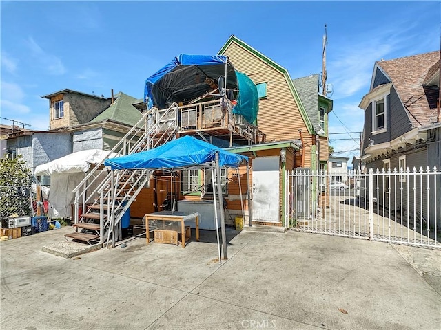 rear view of house with fence, a gambrel roof, and a patio area