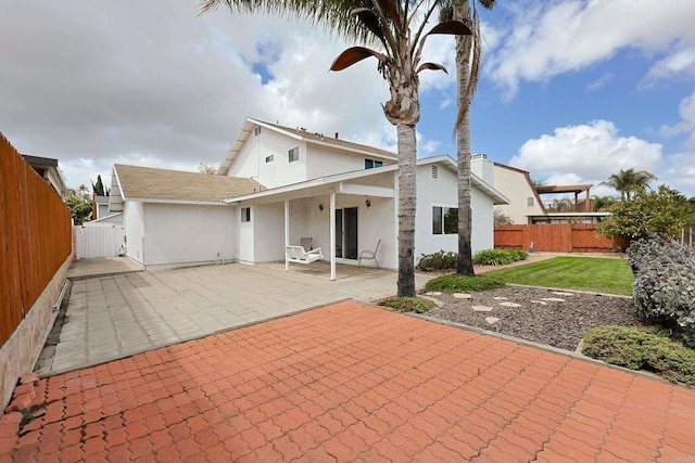 rear view of property with stucco siding, a patio area, and a fenced backyard