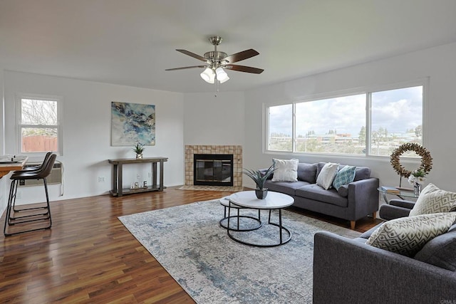 living room with a ceiling fan, a tile fireplace, and dark wood-style flooring