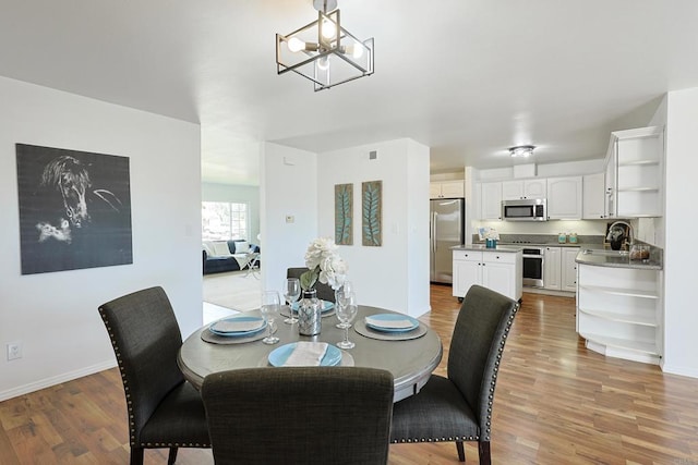 dining area with visible vents, light wood-style flooring, baseboards, and an inviting chandelier