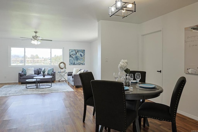 dining space featuring baseboards, wood finished floors, and ceiling fan with notable chandelier