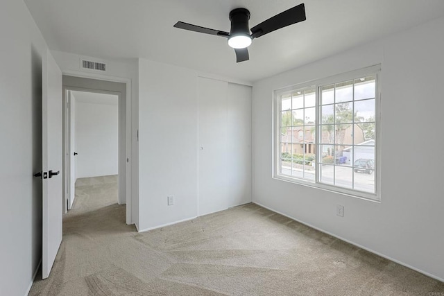 unfurnished bedroom featuring light carpet, visible vents, baseboards, a ceiling fan, and a closet