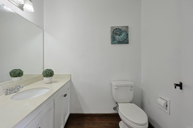 bathroom featuring toilet, vanity, wood finished floors, and baseboards