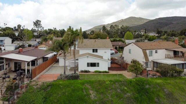 back of house with a fenced backyard, a mountain view, a residential view, and a yard