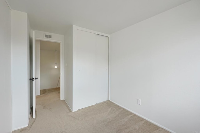 unfurnished bedroom featuring a closet, visible vents, and light carpet