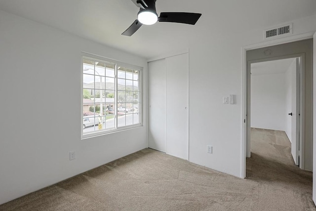 unfurnished bedroom with ceiling fan, carpet floors, visible vents, and a closet