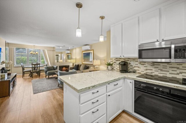 1562 Camino Del Mar Unit 643, Del Mar, CA 92014 - kitchen featuring black appliances, a peninsula, white cabinetry, backsplash, and light wood finished floors