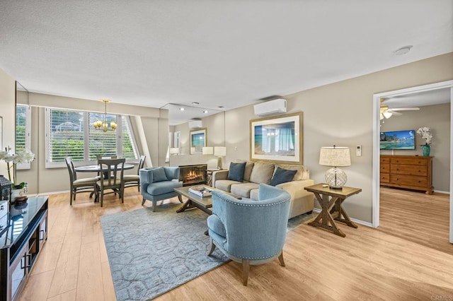 1562 Camino Del Mar Unit 643, Del Mar, CA 92014 - living room featuring a wall mounted air conditioner, light wood-style flooring, baseboards, and a glass covered fireplace