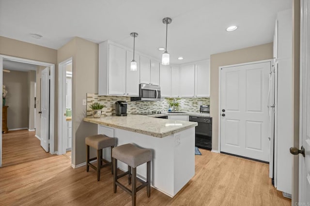 1562 Camino Del Mar Unit 643, Del Mar, CA 92014 - kitchen with dishwasher, a peninsula, stainless steel microwave, white cabinetry, and tasteful backsplash