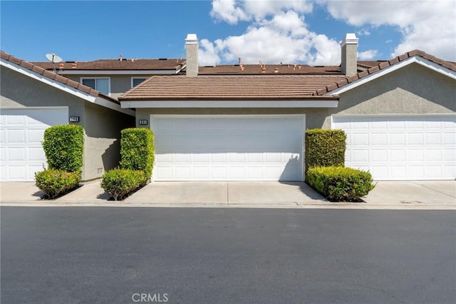 581 Springbrook N, Irvine, CA 92614 - townhome / multi-family property featuring an attached garage, a tiled roof, stucco siding, and a chimney