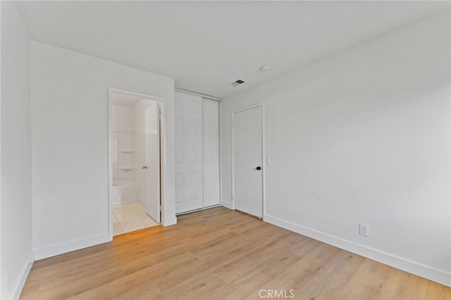 581 Springbrook N, Irvine, CA 92614 - unfurnished bedroom featuring a closet, ensuite bath, light wood-style floors, and baseboards