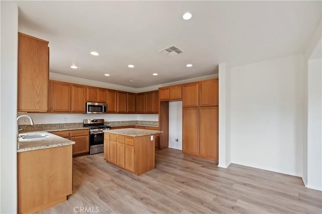 1984 Bronte Rd, San Jacinto, CA 92583 - kitchen with light stone counters, a sink, light wood-style flooring, stainless steel appliances, and visible vents